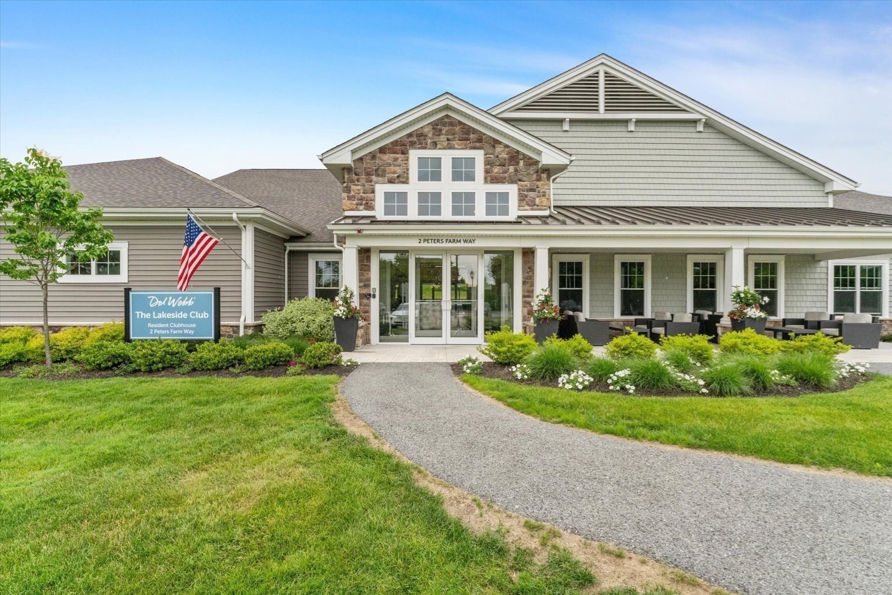 The Lakeside Club resident clubhouse, with stone accents, covered patio seating, and landscaped grounds.