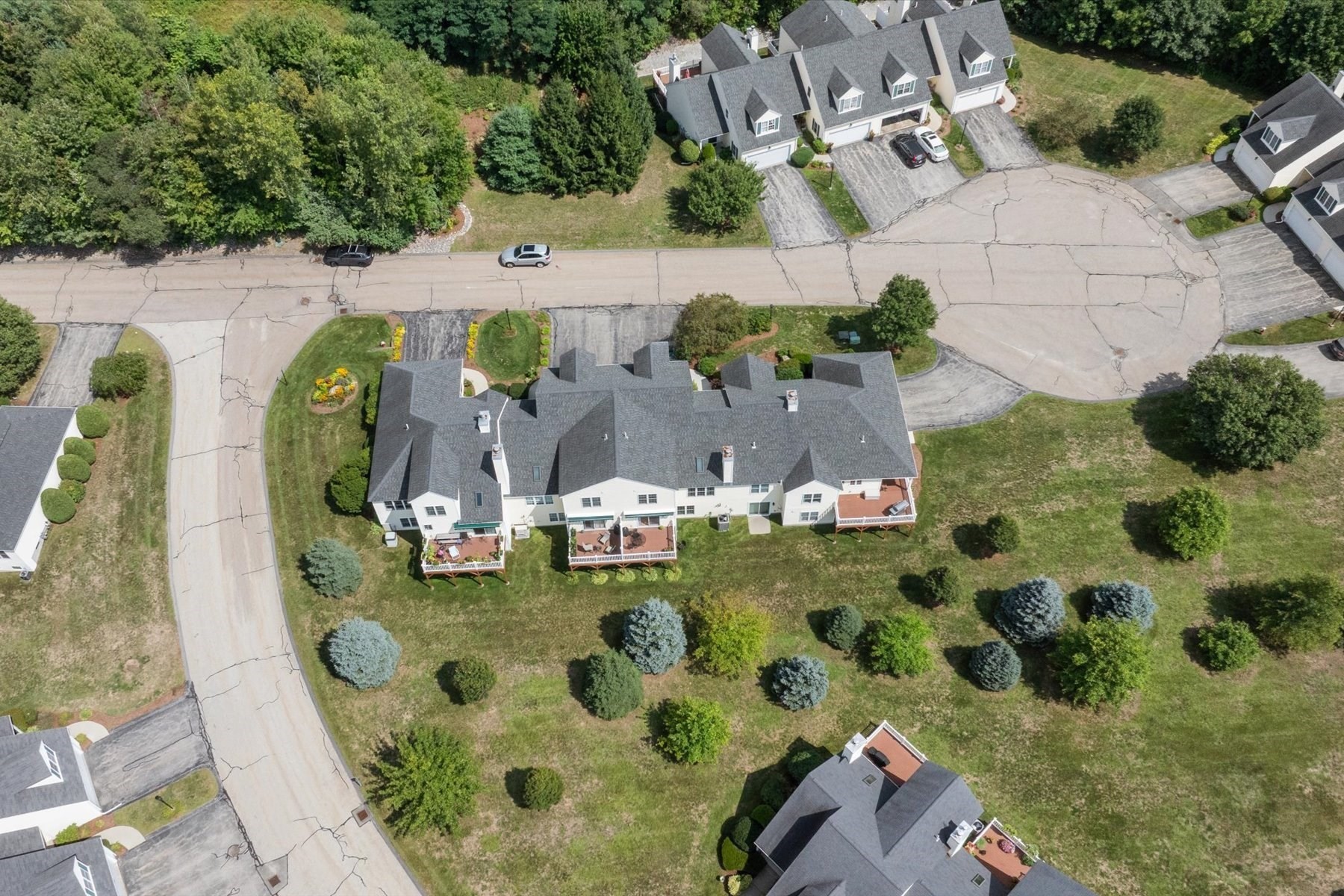 Aerial view of attached condominium homes with rear decks and landscaped grounds.