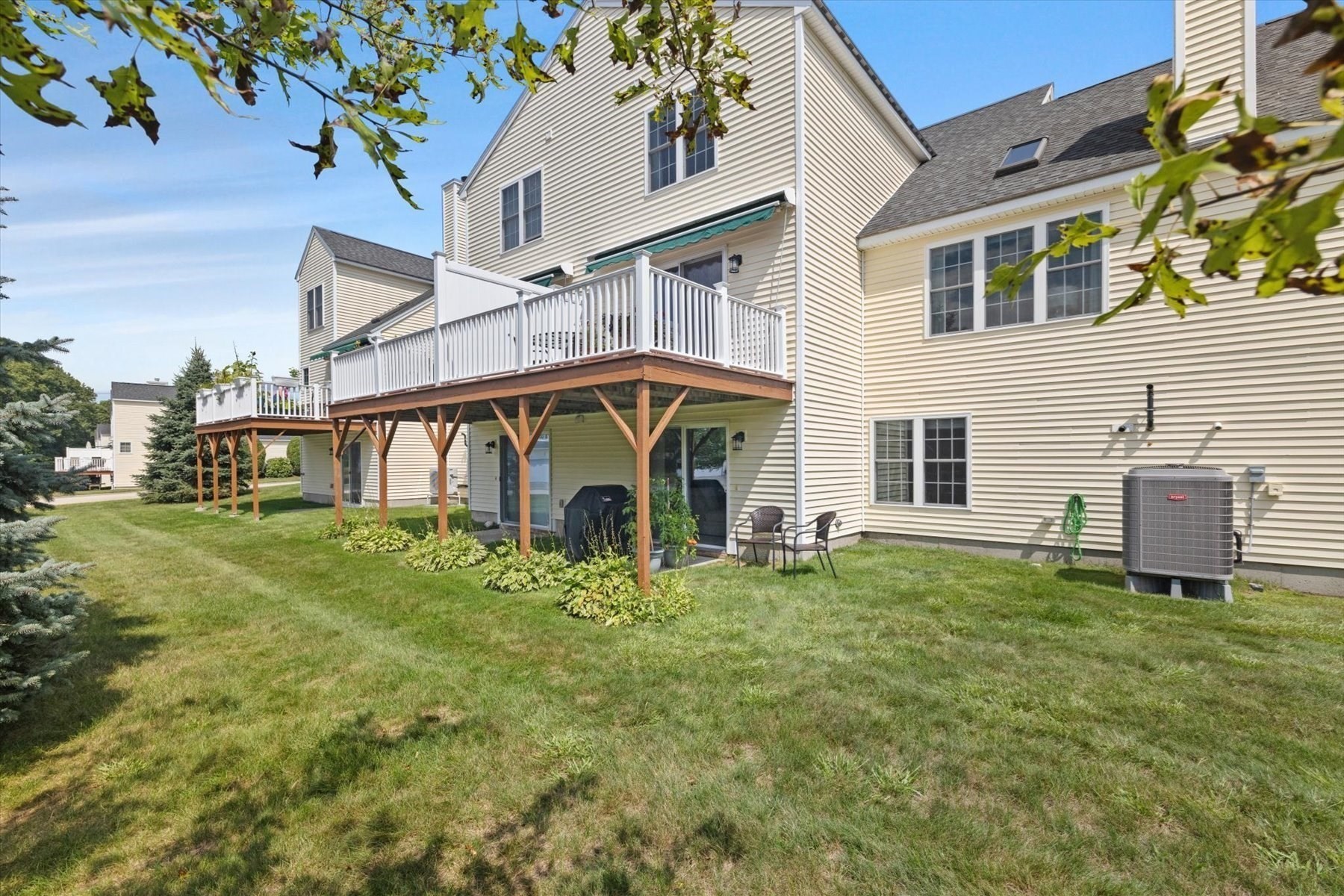 Rear of a light-sided home with a raised deck overlooking a grassy yard.