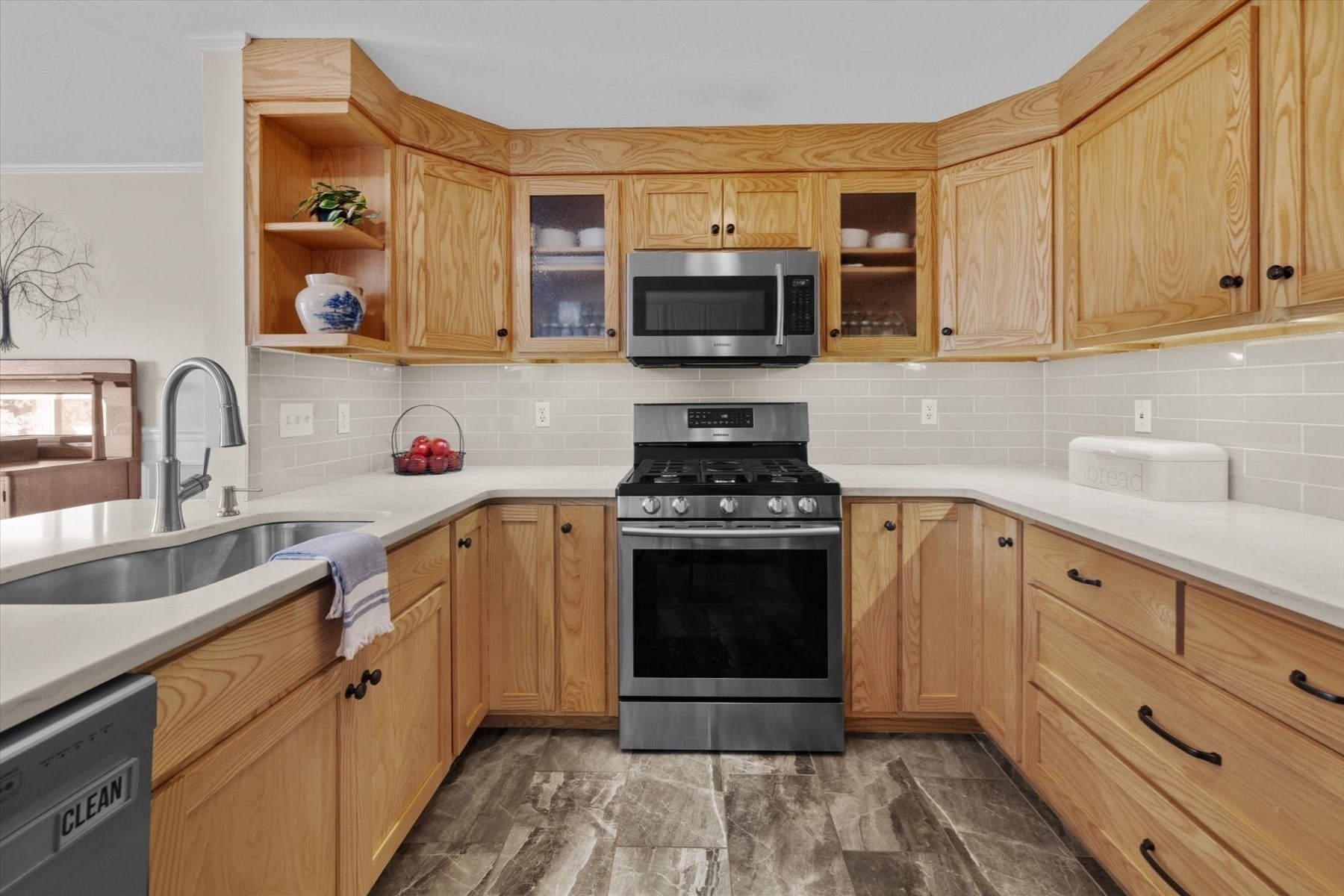 Kitchen with honey-colored wood cabinets, stainless steel appliances, and a gray tile backsplash.