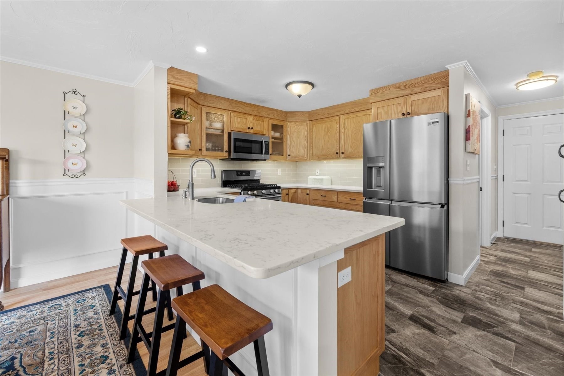 Kitchen with a large white island, natural wood cabinets, and stainless steel appliances.
