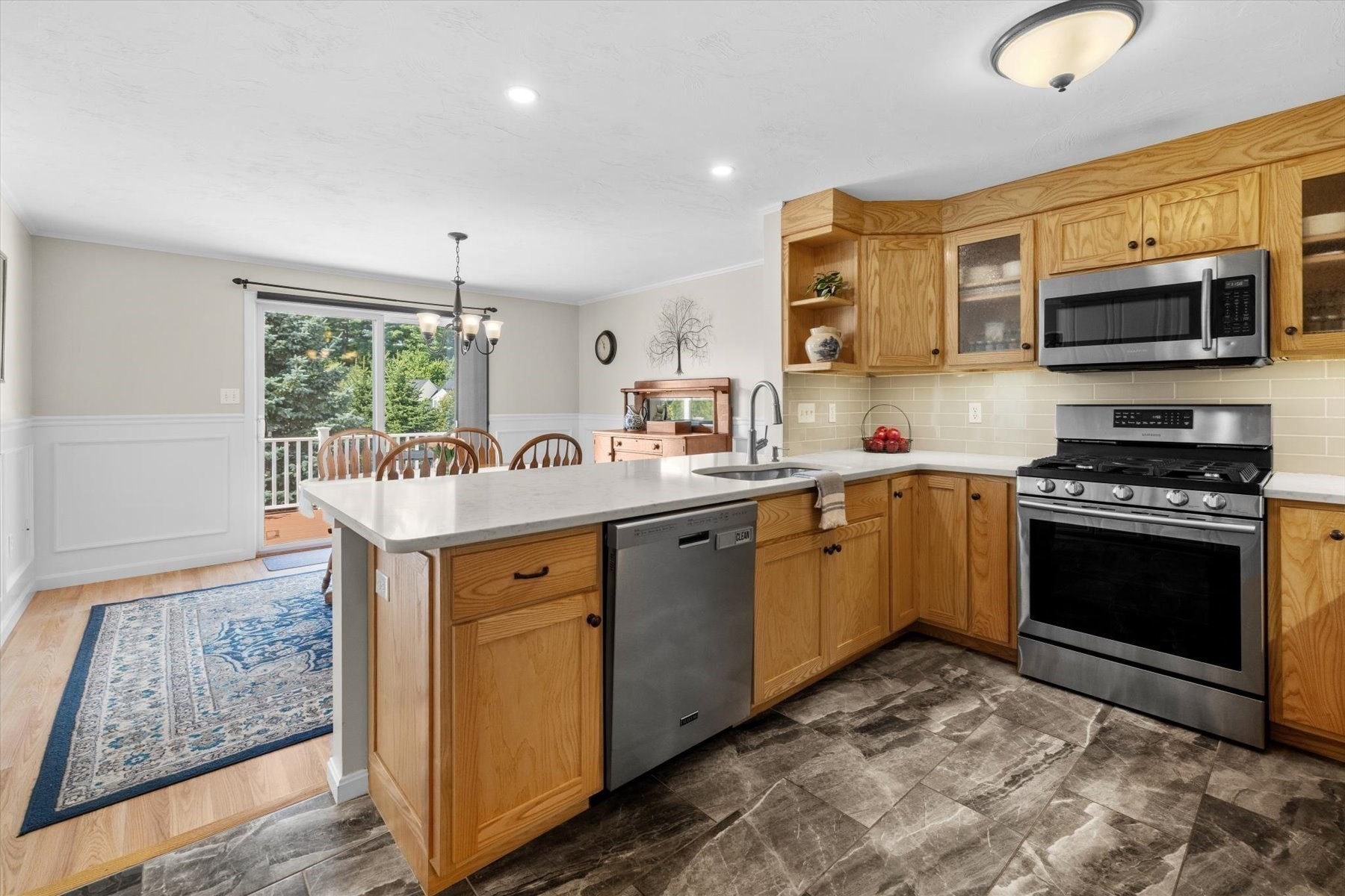 Kitchen with a large island, honey-colored wood cabinets, stainless appliances, and an adjoining dining area.