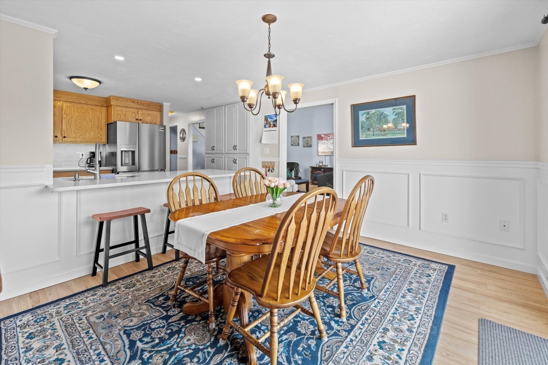 Dining area with a wooden table and chairs beside an open kitchen with stainless steel appliances.