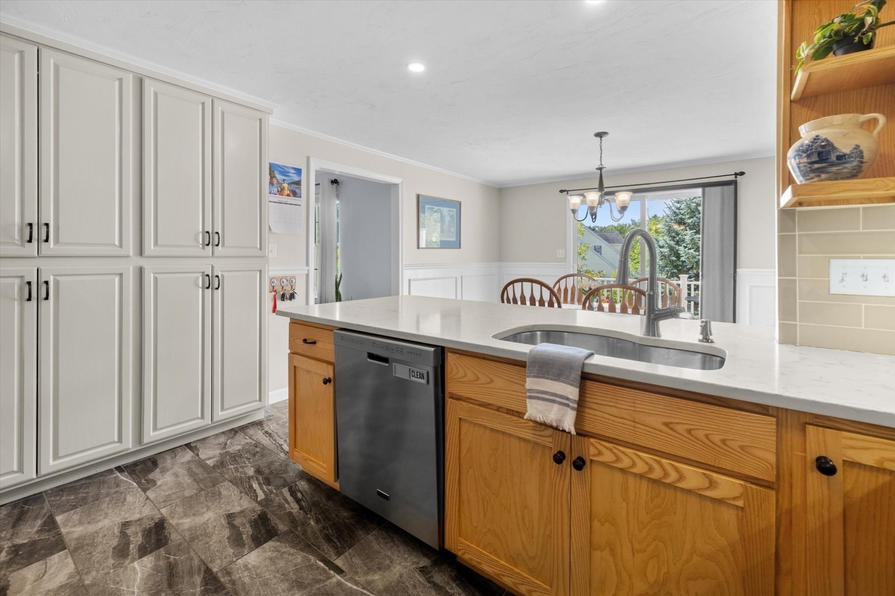 Kitchen with white cabinets, a wood-front island, stone countertop, and sliding glass door by the dining area.