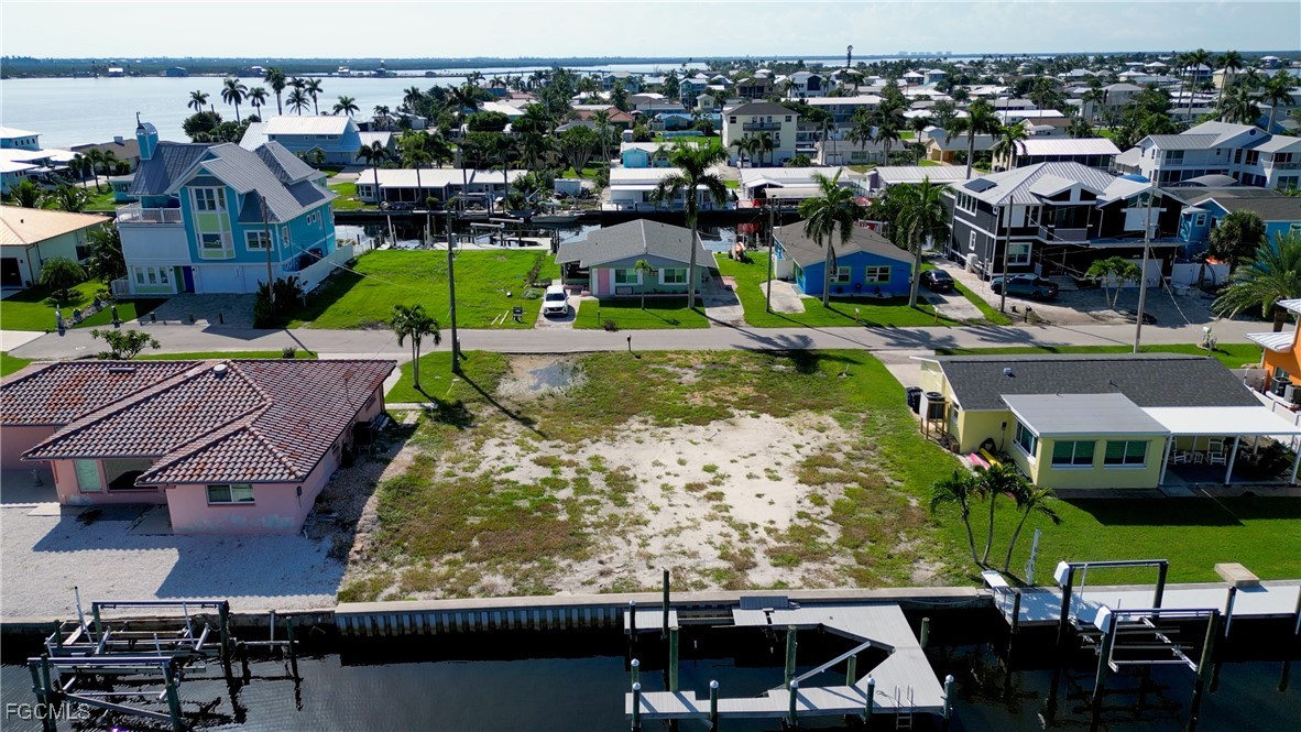 Vacant waterfront lot bordered by a canal and neighboring homes with docks.
