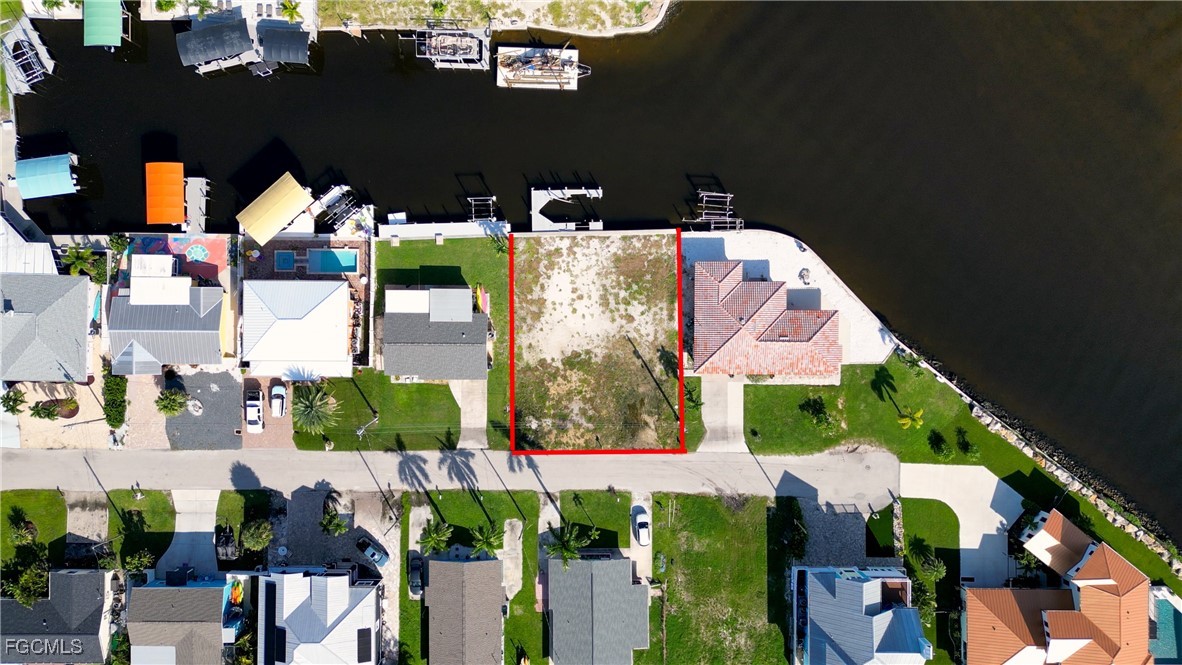Vacant canal-front lot outlined in red, between homes with docks.