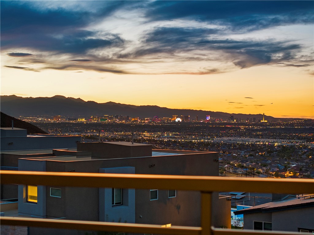 Las Vegas skyline at dusk viewed over nearby homes from a hillside property.
