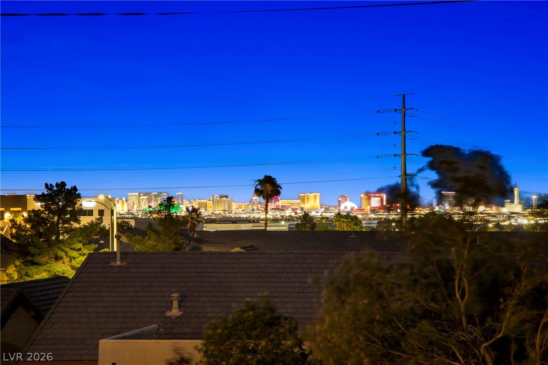 Las Vegas Strip skyline at dusk, viewed beyond nearby rooftops and trees.