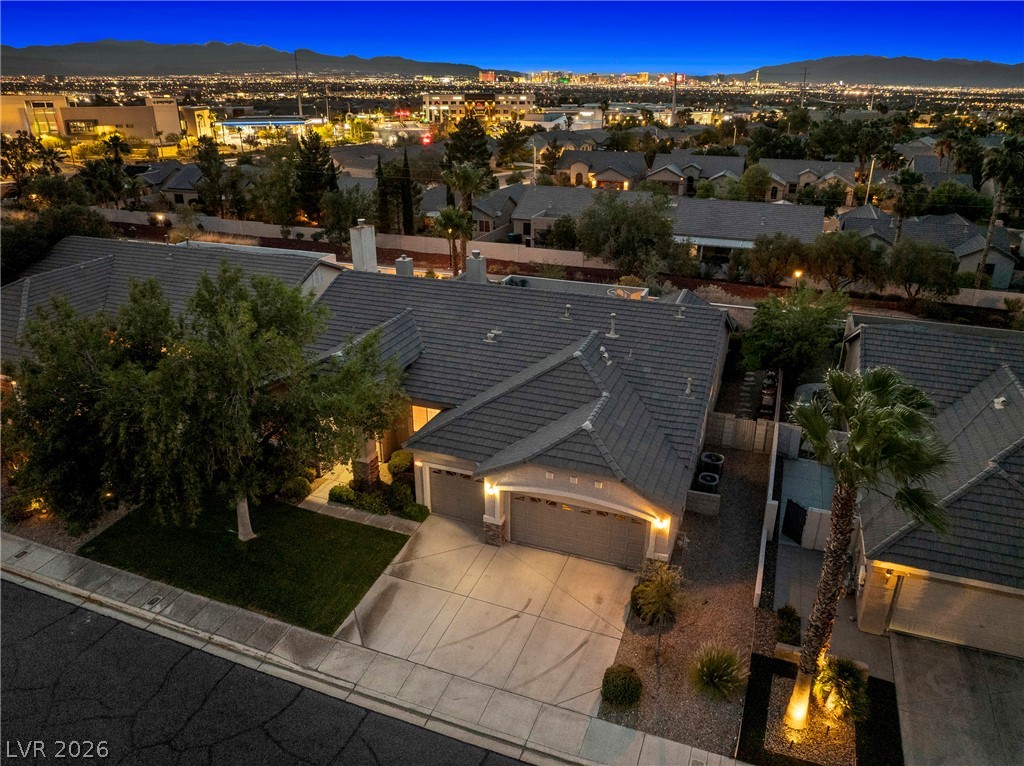 Aerial view of a Henderson home at dusk, with city lights and mountains beyond the neighborhood.