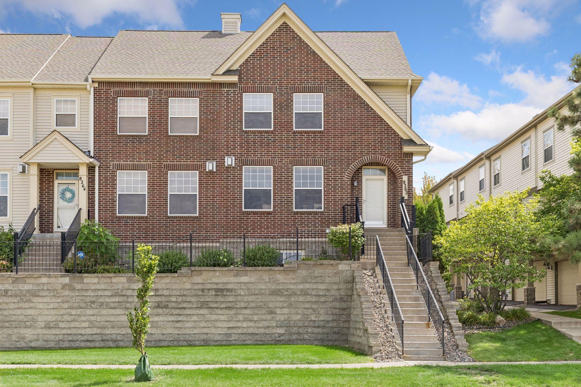 Red-brick townhouse exterior with a raised stone wall and stairs to the entrance.