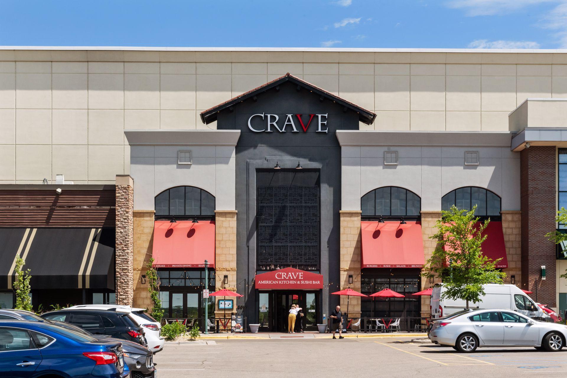CRAVE restaurant storefront with red awnings, arched windows, and a central dark entrance.