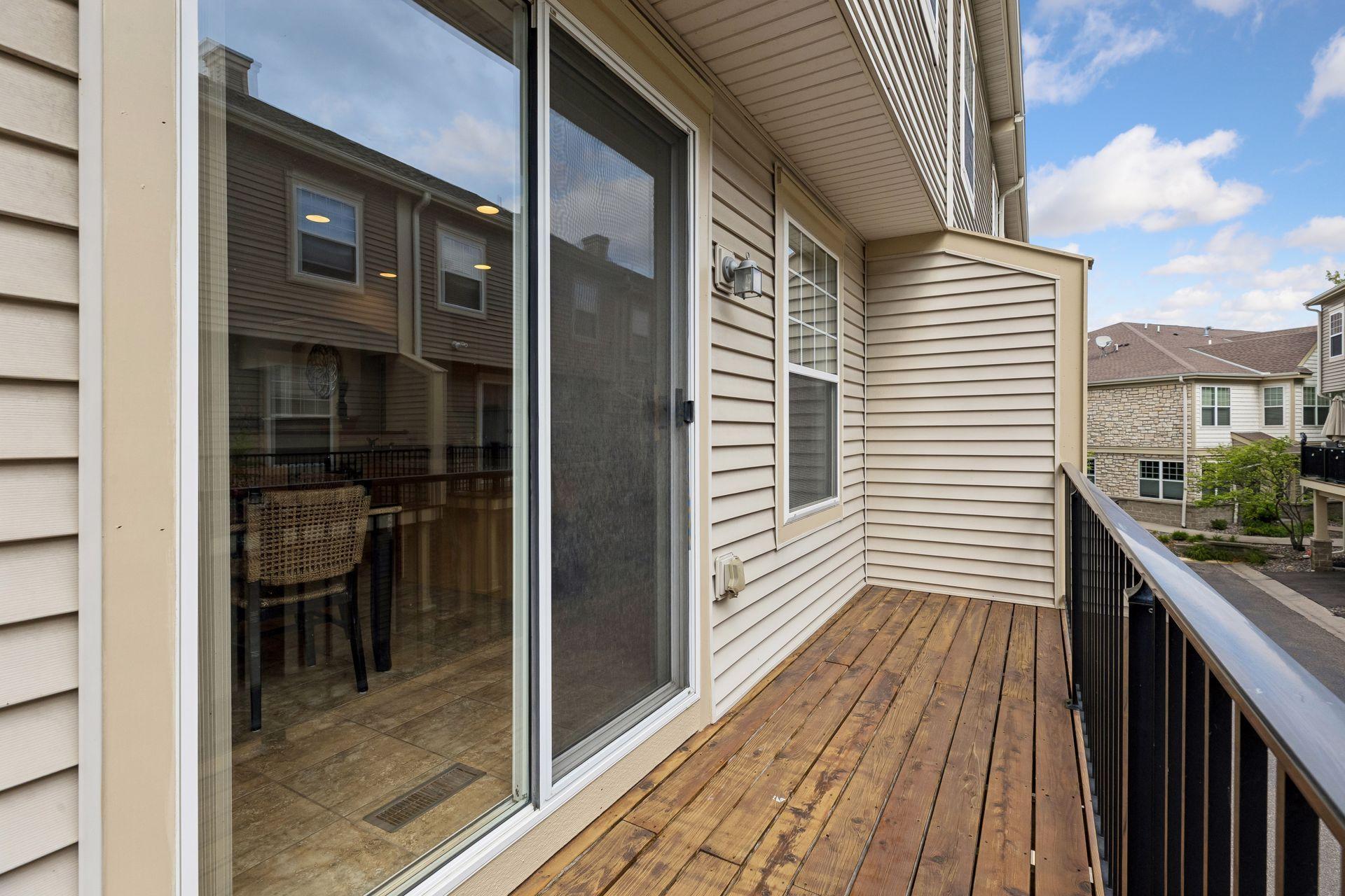 Townhouse balcony with wood decking, black railing, and sliding glass door.