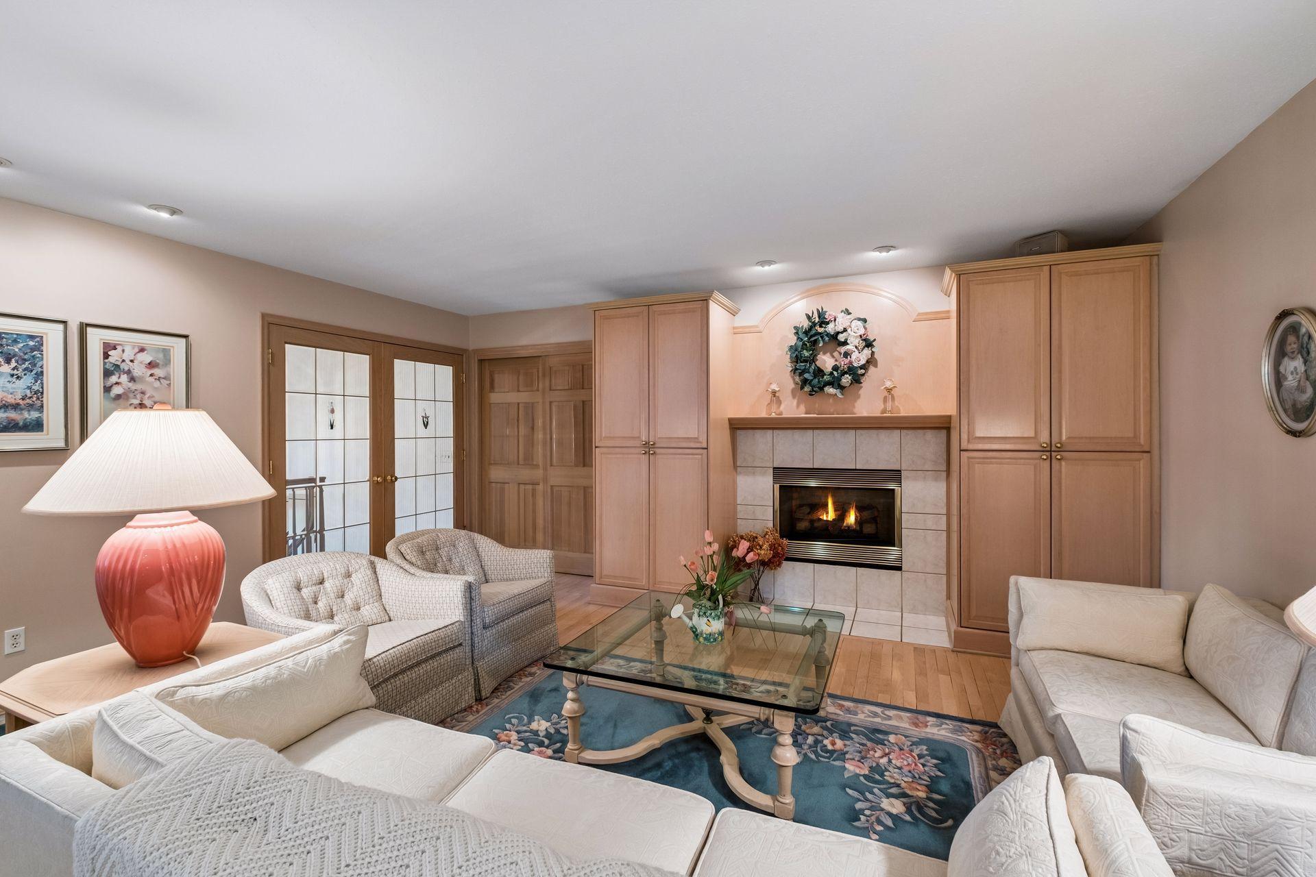 Furnished living room with a tiled fireplace, built-in cabinets, and seating around a glass coffee table.