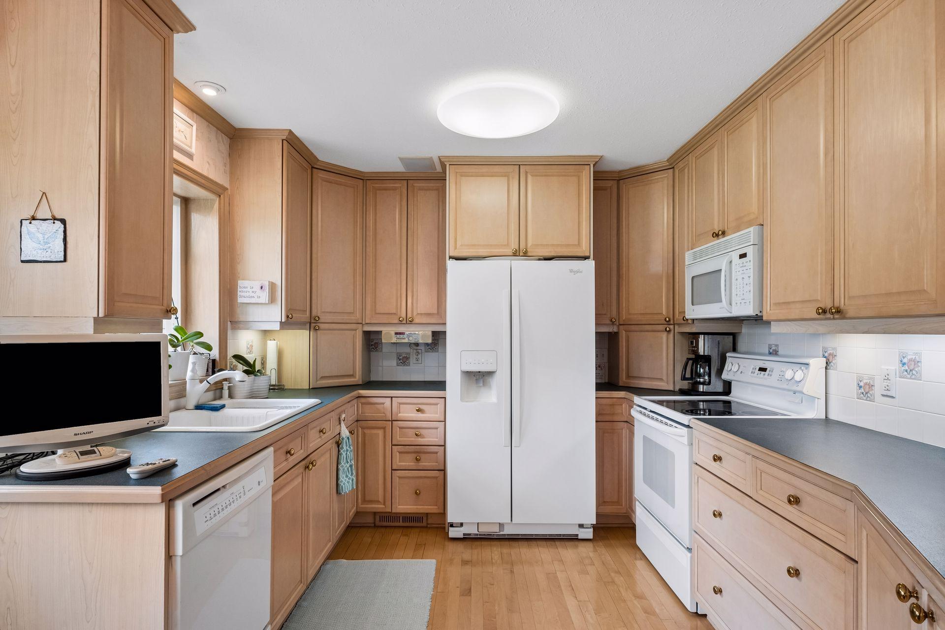 Kitchen with light wood cabinets, blue-gray counters, and white appliances.