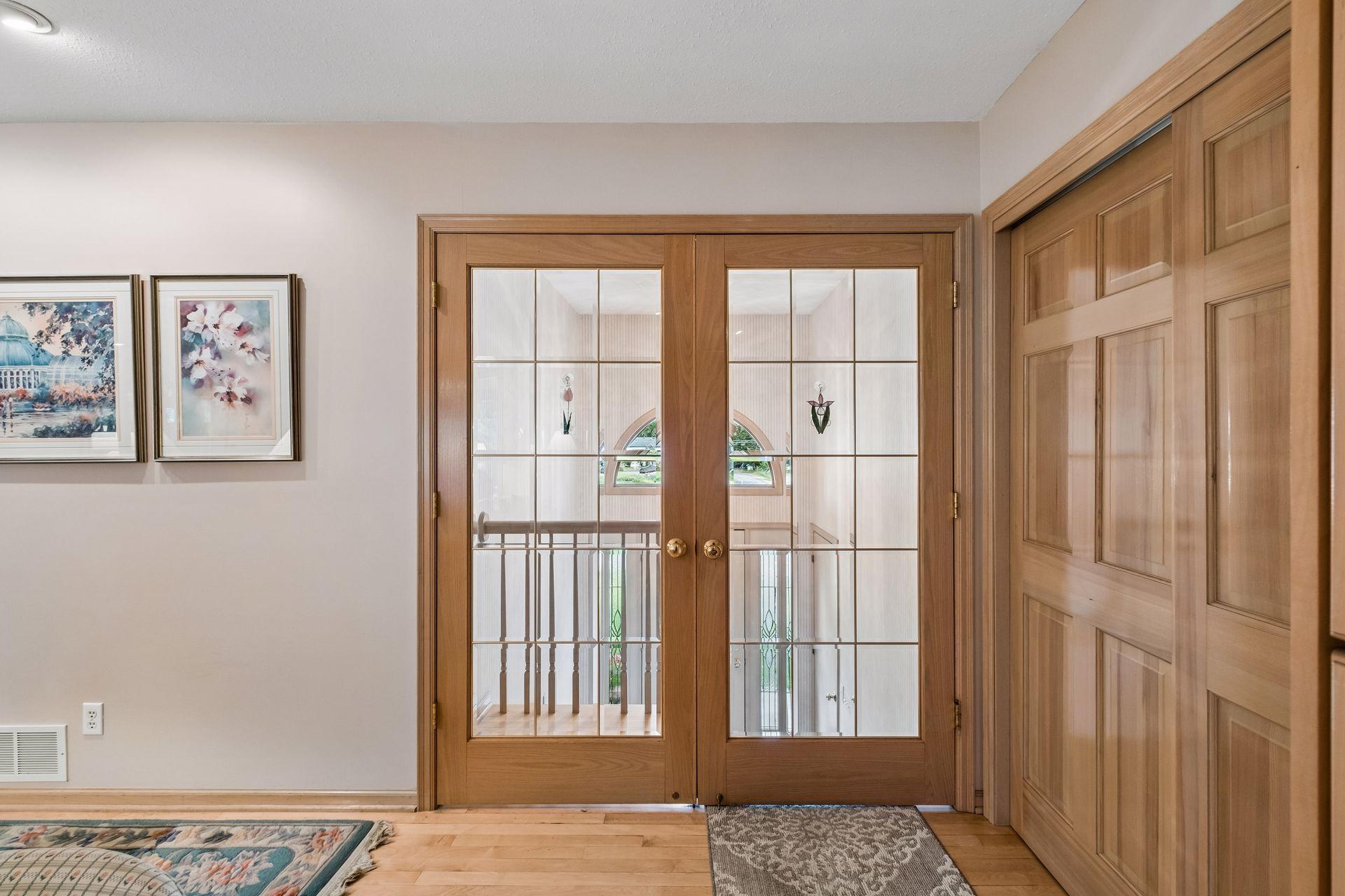 Entryway with wood-framed glass double doors and a paneled wooden closet door.