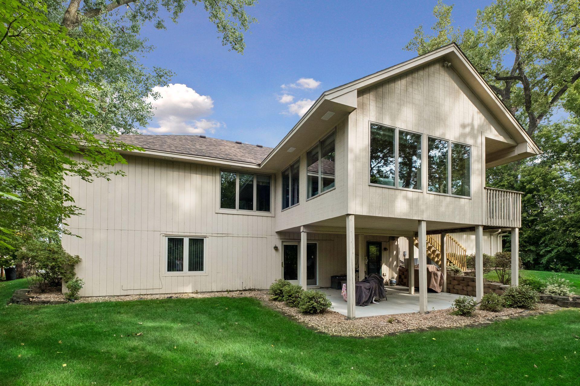 Rear of a light-colored split-level house with a raised deck and covered patio.