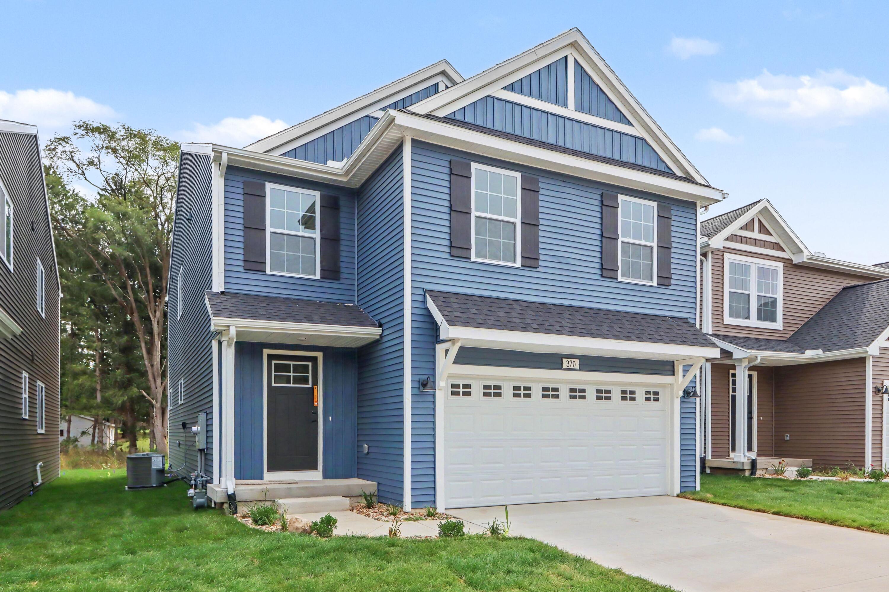 Blue two-story house with white trim, steep gables, and an attached two-car garage.
