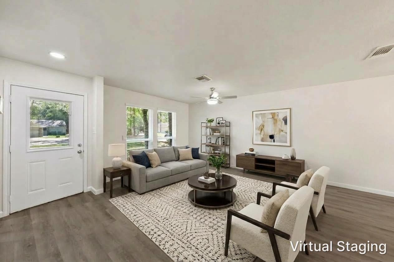 Living room with gray sofa, cream armchairs, and a round coffee table on a patterned rug.