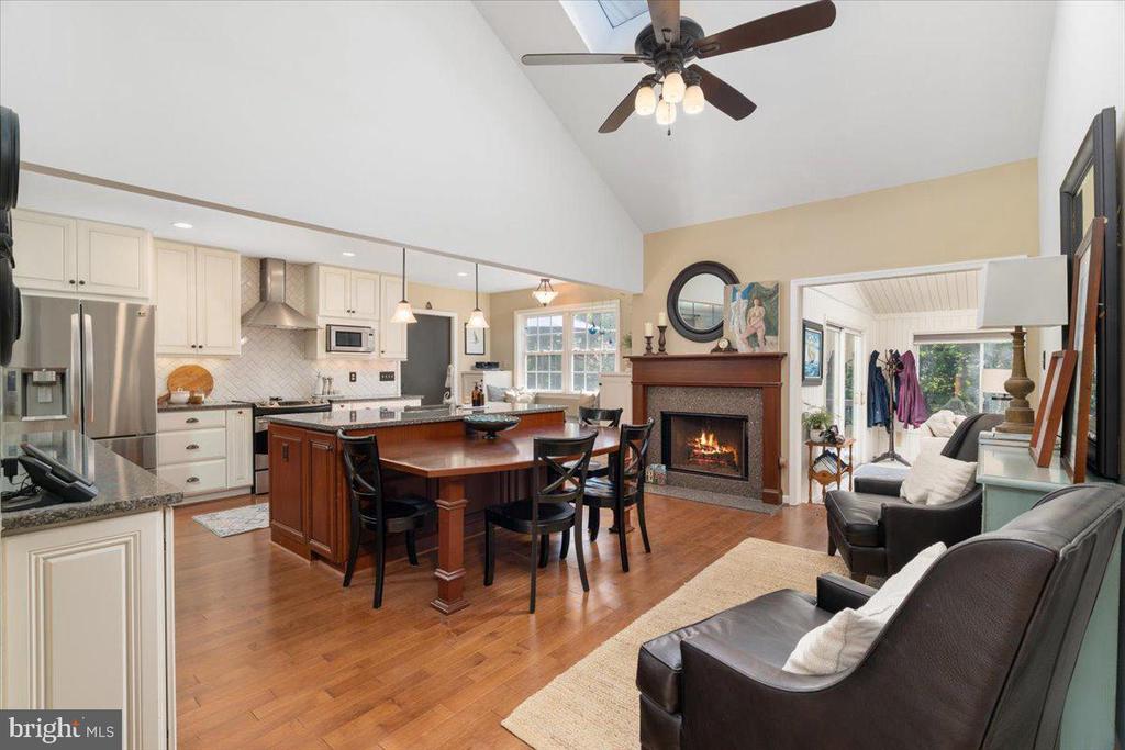 Open-plan kitchen and living room with a wood-topped island and lit fireplace.