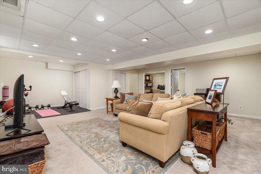 Furnished basement recreation room with a sectional sofa and a small home gym area.