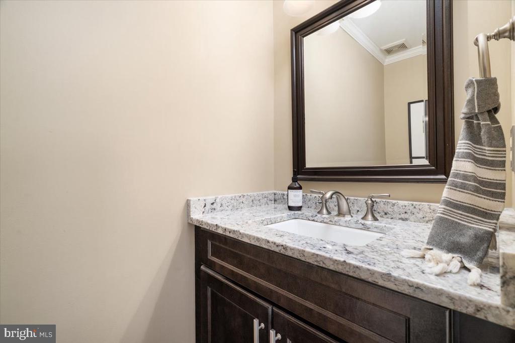 Bathroom vanity with a granite countertop, dark wood cabinet, and large framed mirror.