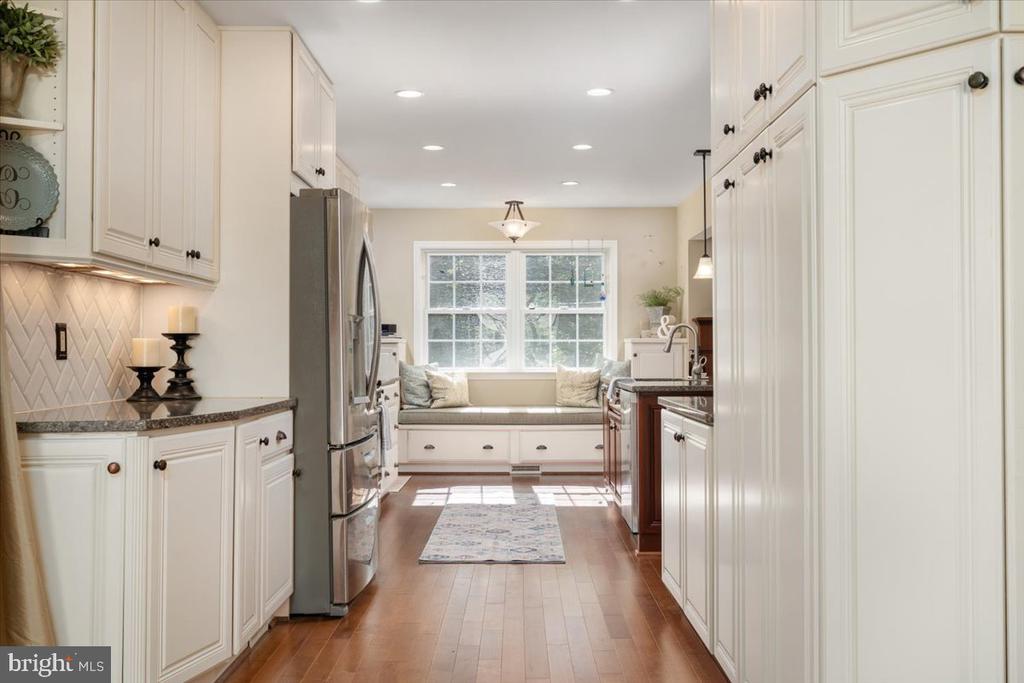 Bright kitchen with white cabinetry, stainless steel appliances, and a cushioned window seat.