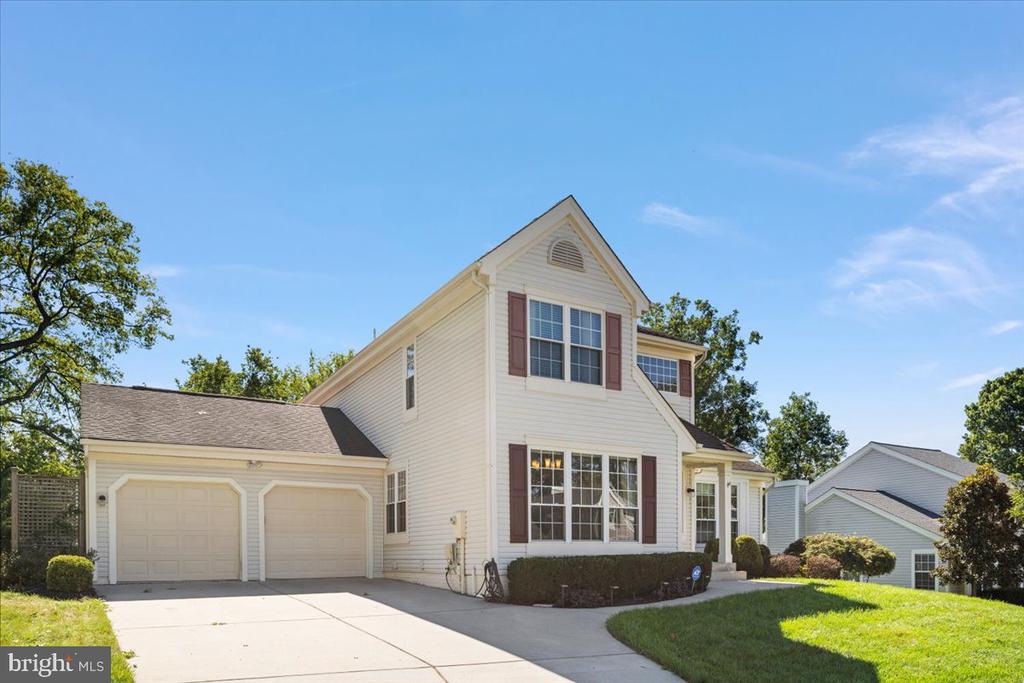 White two-story home with brown shutters, an attached two-car garage, and a broad concrete driveway.