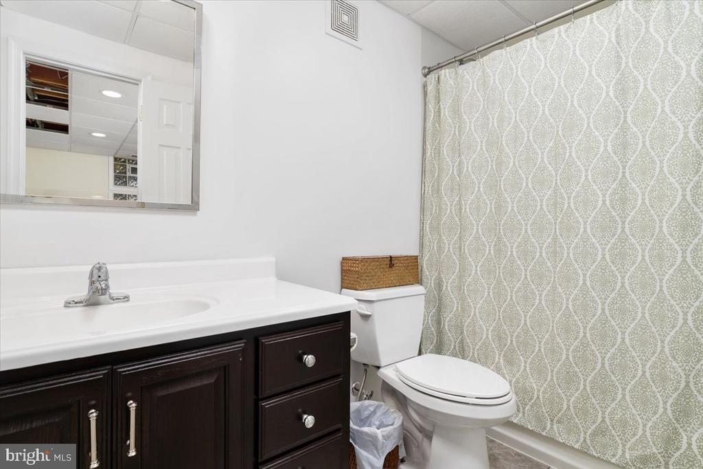 Bathroom with a dark wood vanity, white countertop, and patterned shower curtain.