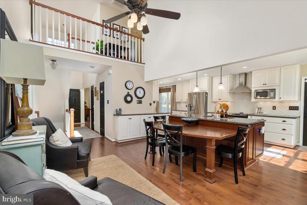 Open-plan kitchen and living room with a large wood island, white cabinetry, and an overhead loft.