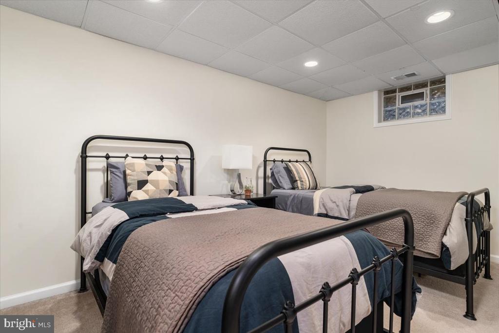 Staged bedroom with two black metal twin beds and patterned gray and navy bedding.