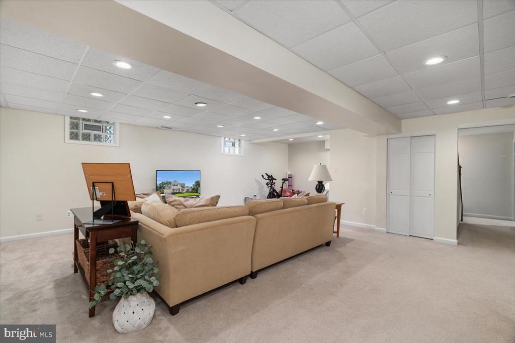 Finished basement recreation room with a beige sectional sofa, television, and exercise bike.