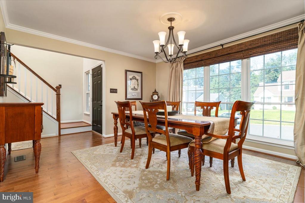 Dining room with a wooden table, chandelier, and broad windows overlooking the lawn.