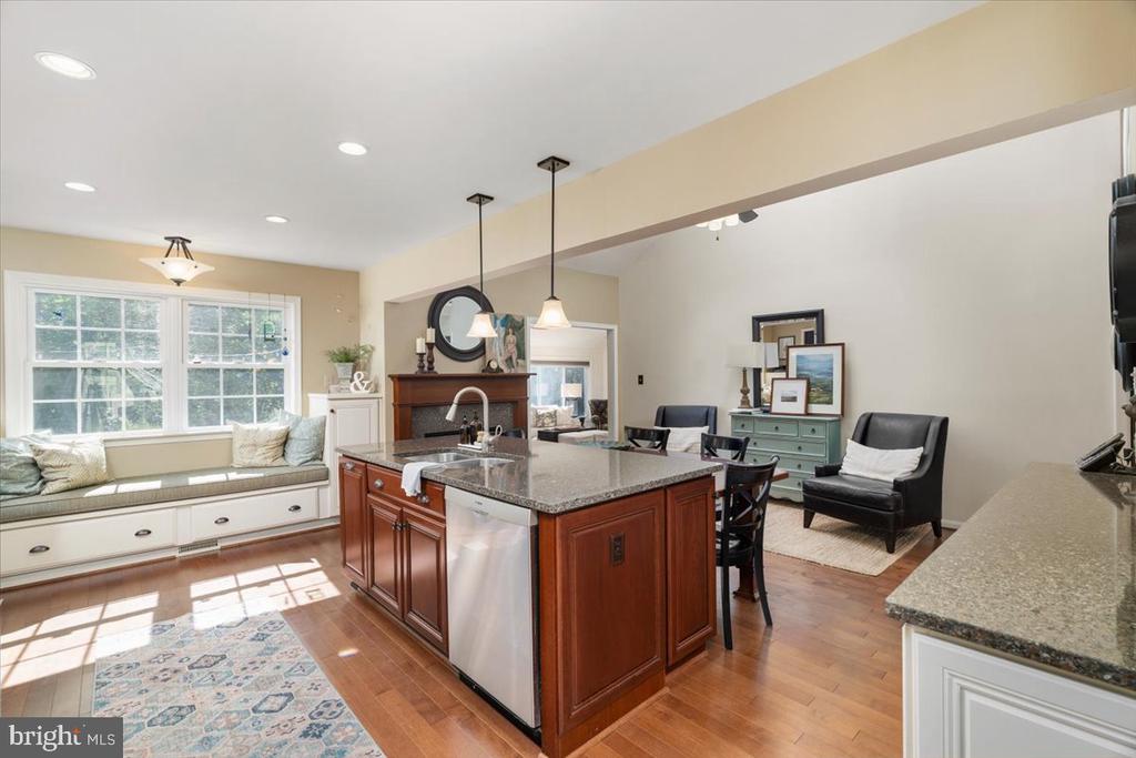 Open-plan kitchen with a cherry-wood island, granite counters, window seat, and fireplace.