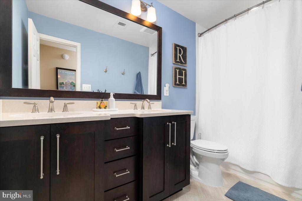 Bathroom with a dark wood double vanity, large mirror, blue walls, and a white shower curtain.