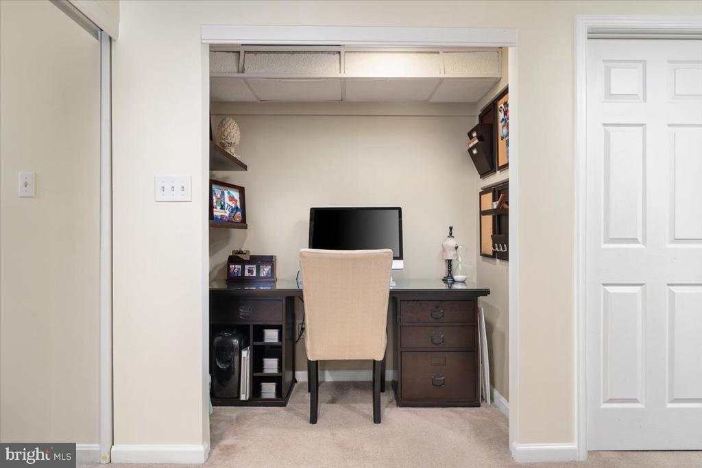Furnished home office nook with a dark desk, computer monitor, beige chair, and built-in shelves.