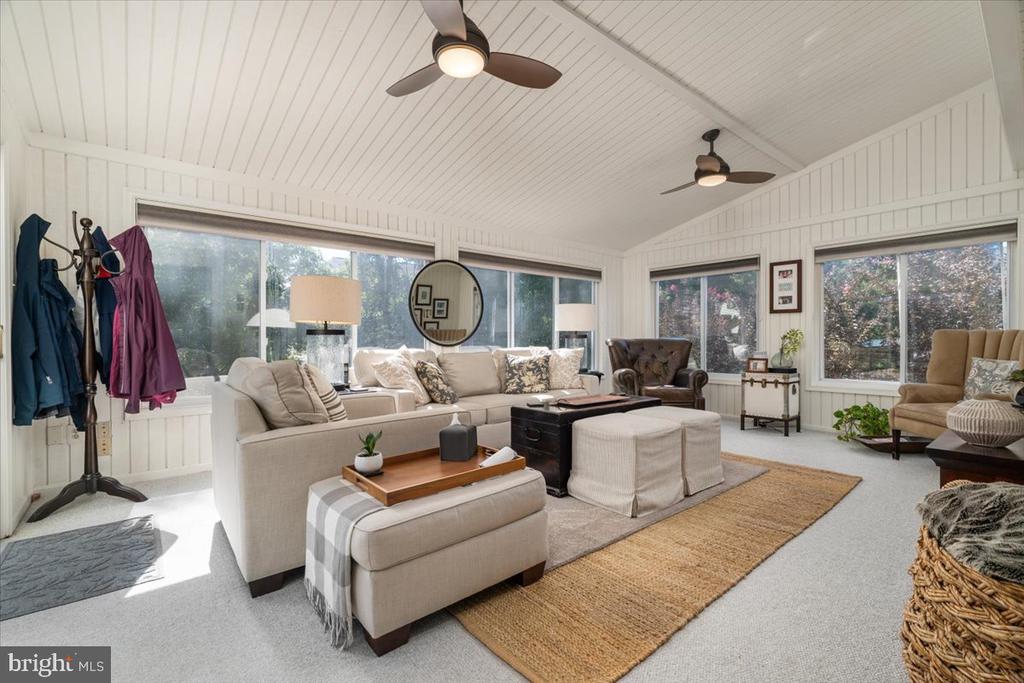 Living room with a vaulted beadboard ceiling, large windows, and a neutral sectional sofa.