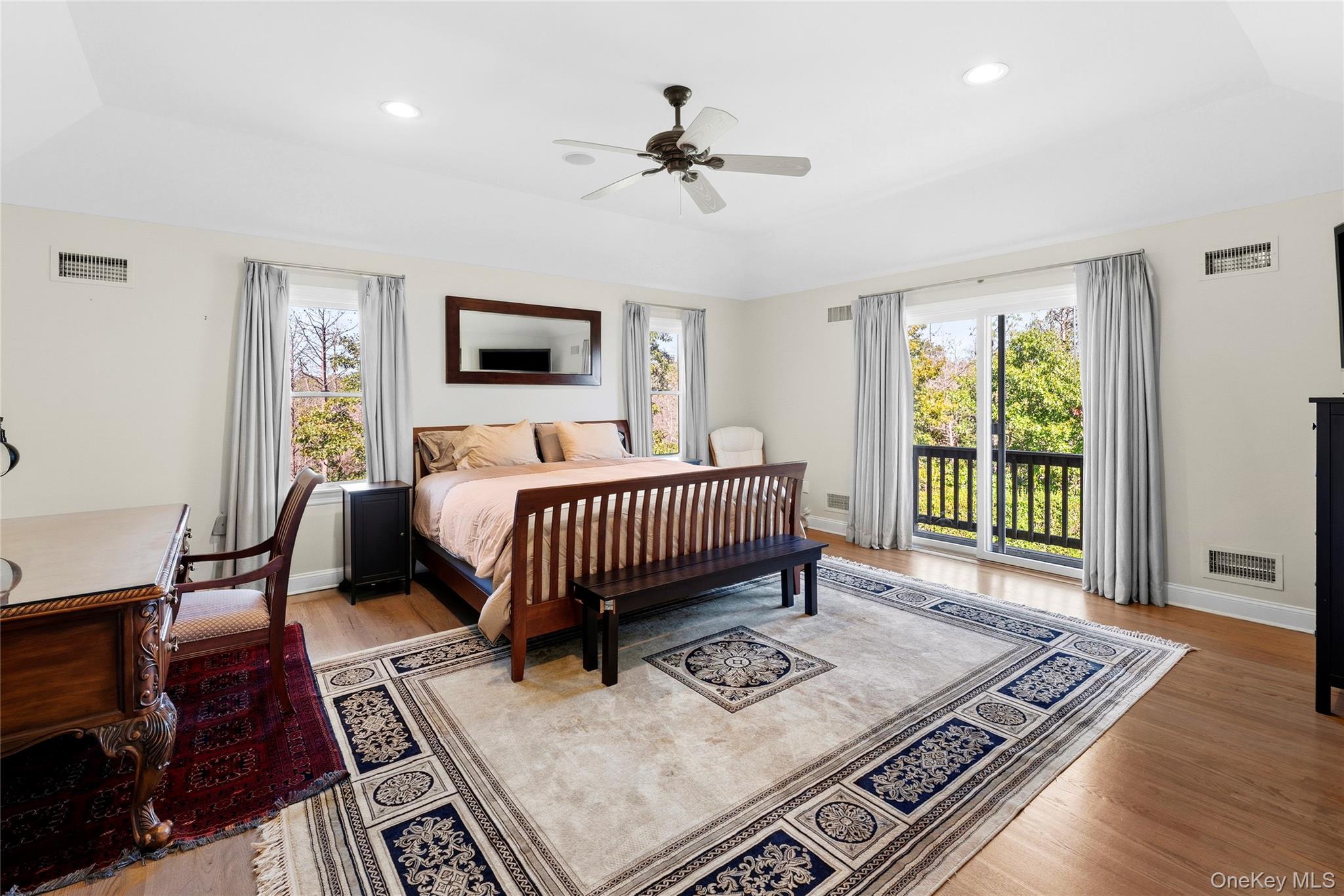 Bedroom with a dark wood bed, patterned rug, and sliding glass doors to a balcony.