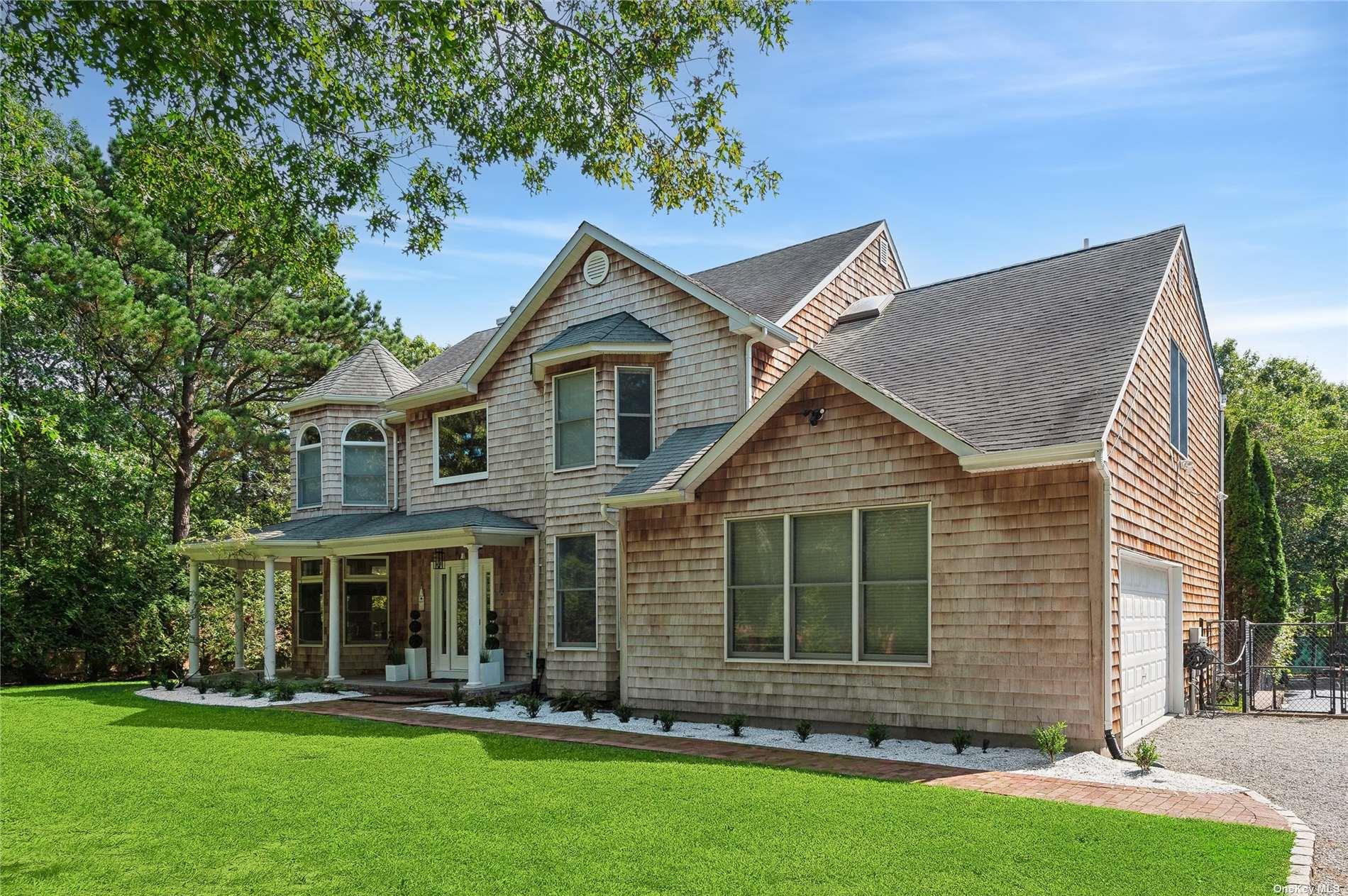 Shingle-sided two-story house with a covered porch, attached garage, and landscaped lawn.