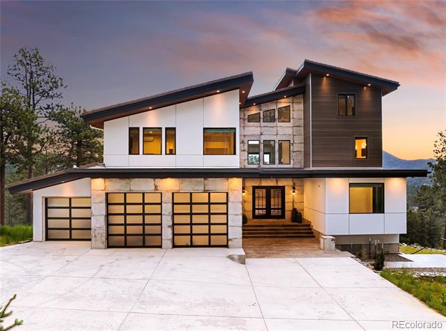 Contemporary home with three garage doors and stone accents, lit at dusk beneath a pink-orange sky.