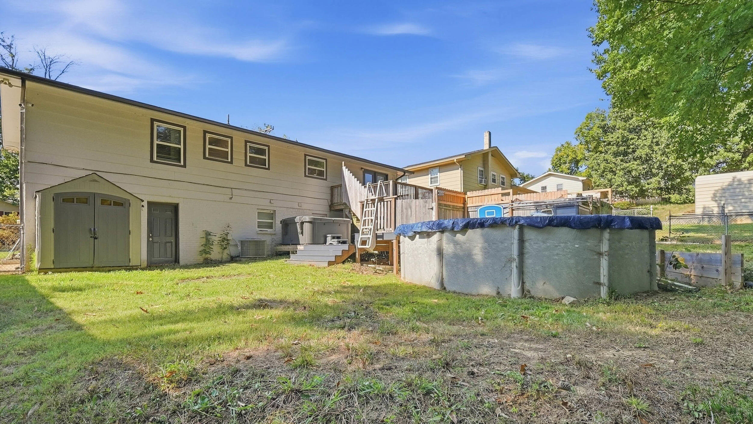 Home’s backyard with an above-ground pool, raised deck, and storage shed.