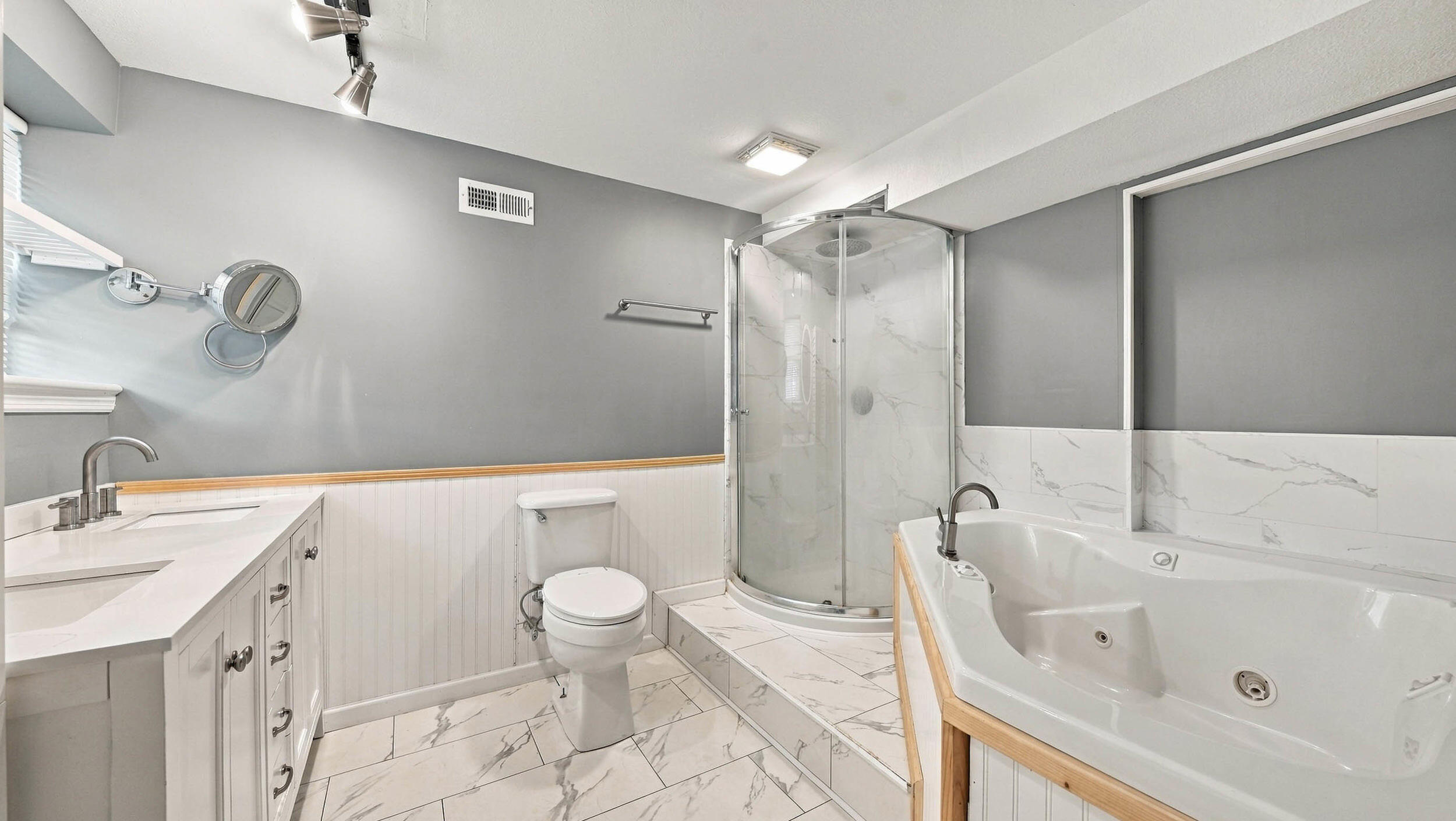 Bathroom with a glass corner shower, jetted tub, and double-sink vanity.