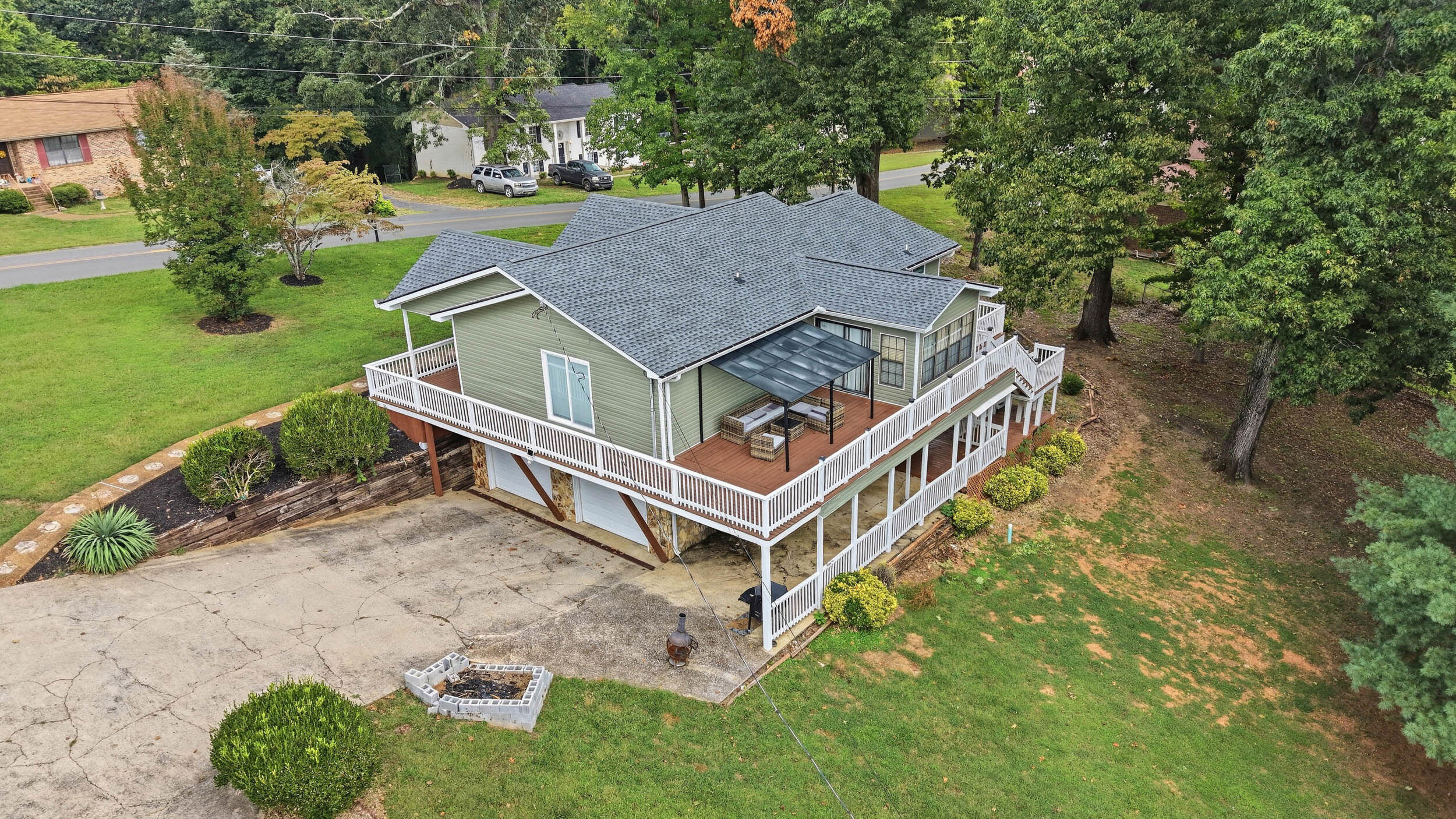Aerial view of a sage-green home with wraparound deck and covered patio.