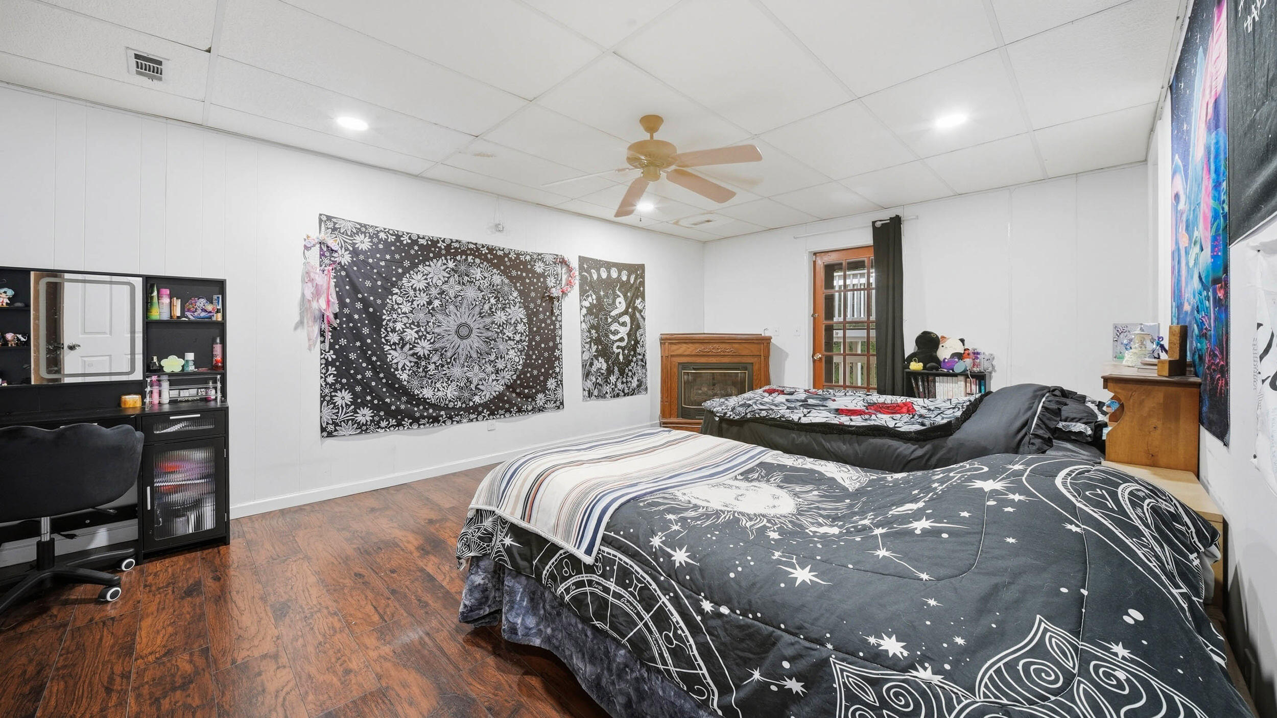 Bedroom with two beds in celestial-patterned bedding and a fireplace at the back wall.