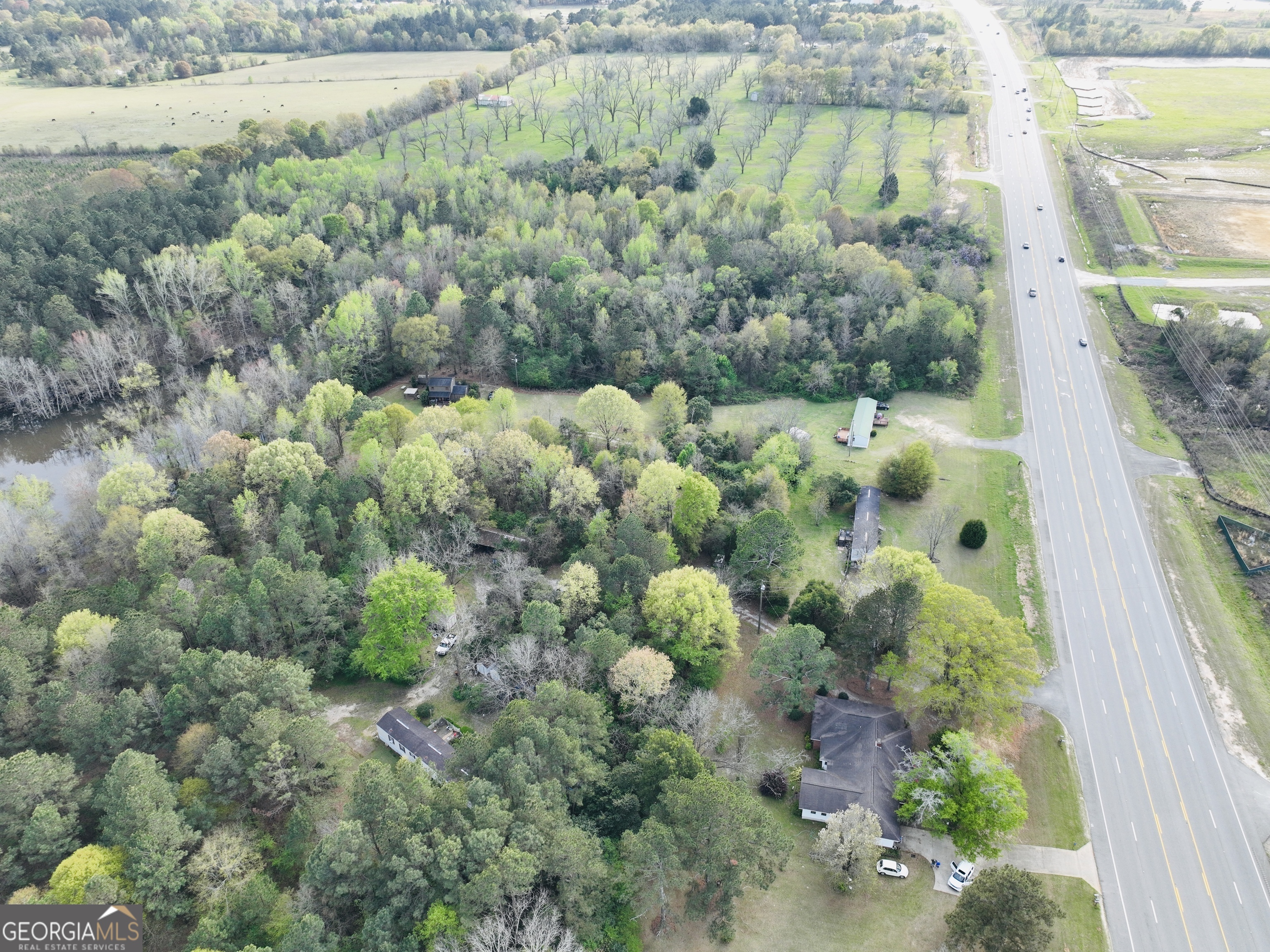 Aerial view of a wooded property with several buildings beside a divided highway.