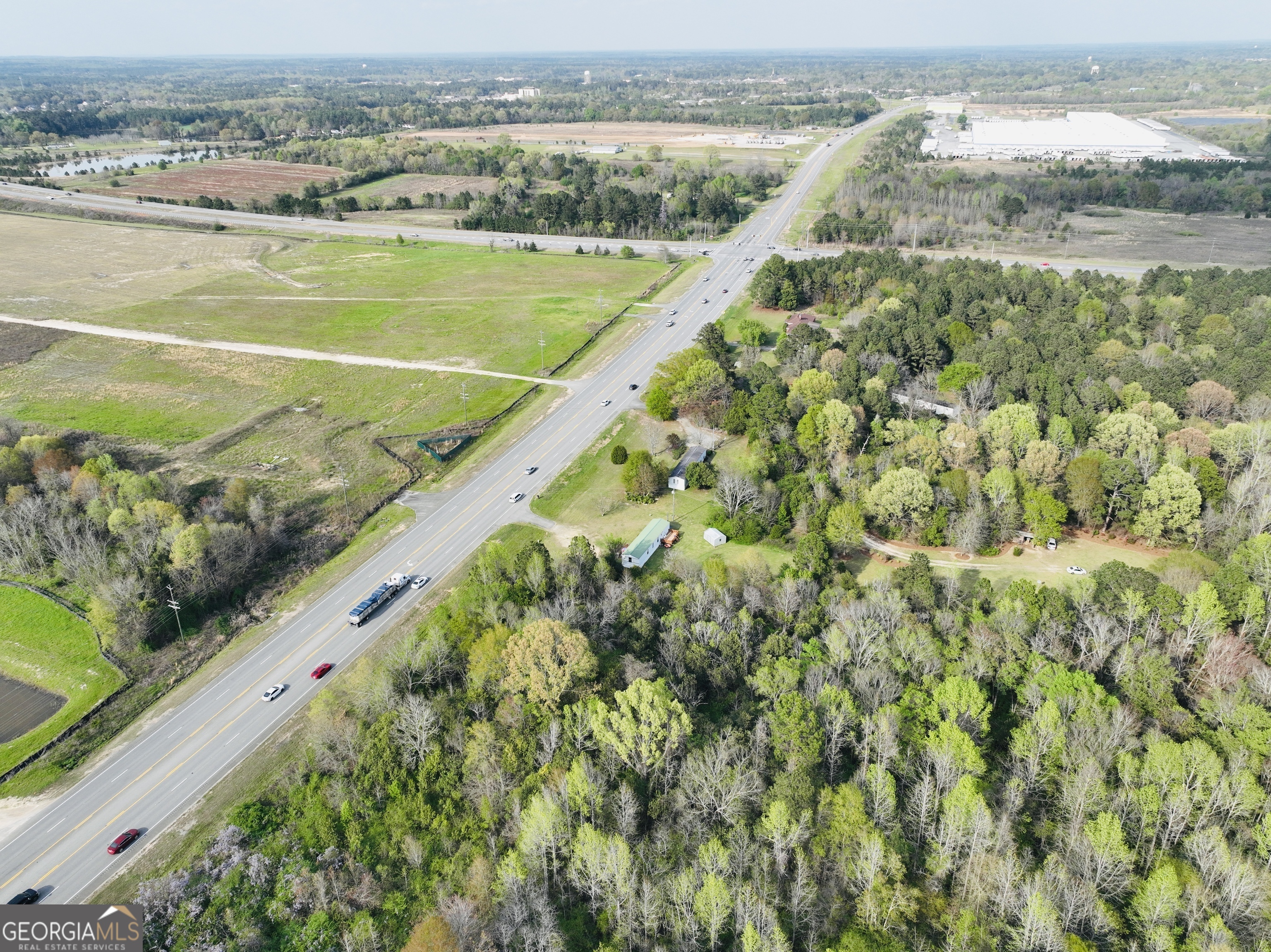 Aerial view of wooded and open land beside a highway intersection.