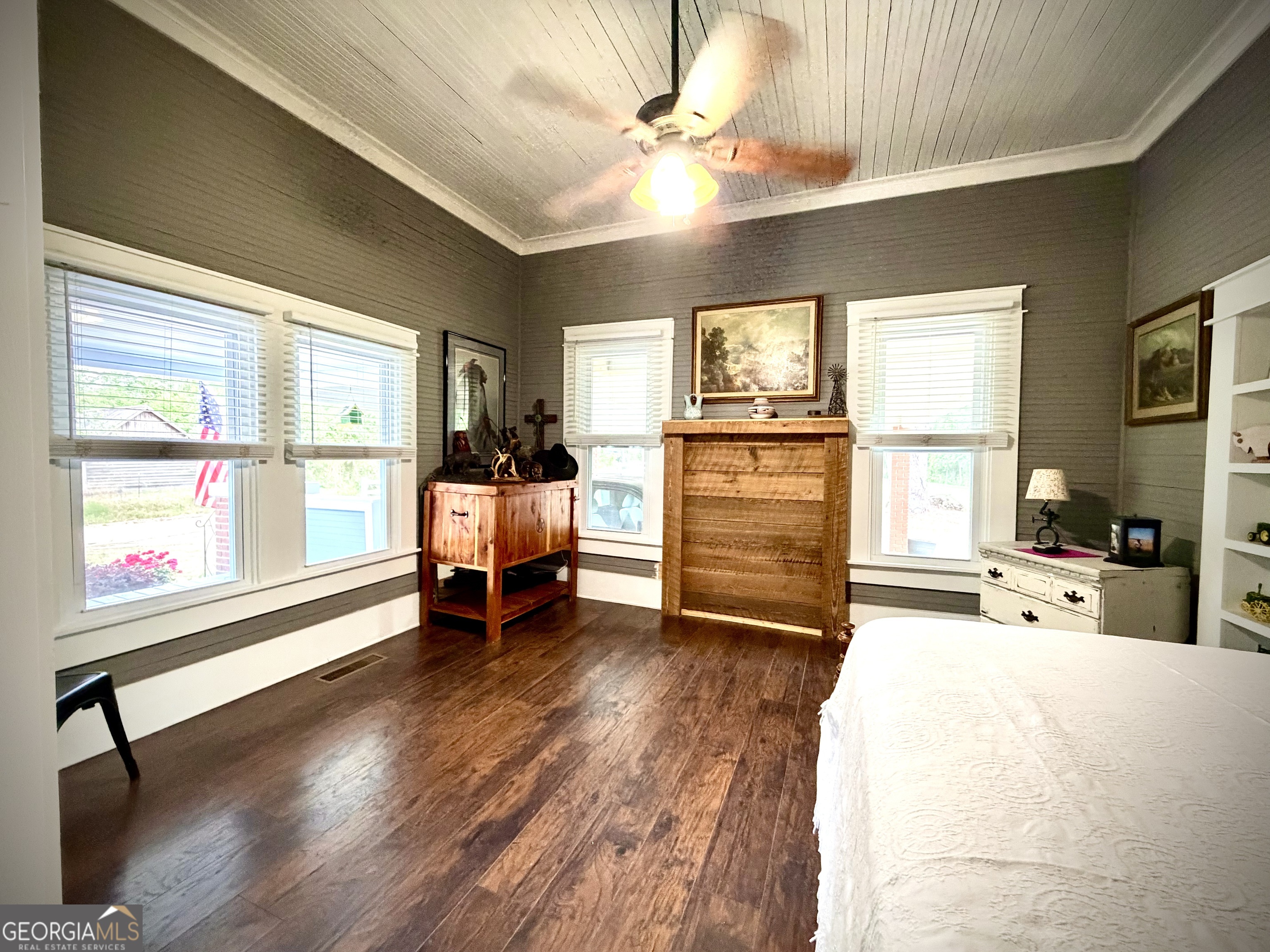 Furnished bedroom with a beadboard ceiling, dark wood floors, and rustic wooden dressers.