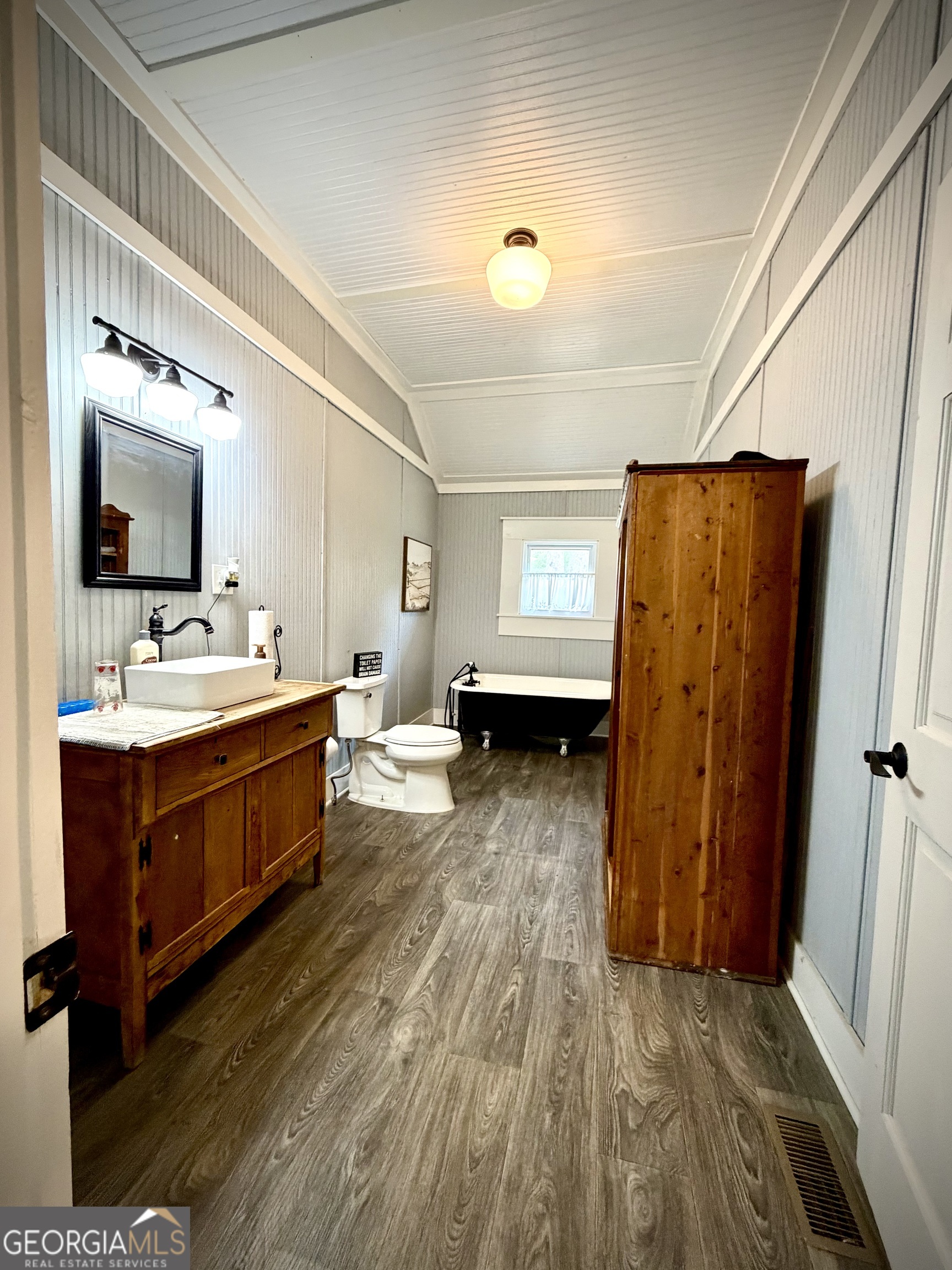 Bathroom with a wooden vessel-sink vanity, black claw-foot tub, and tall wooden cabinet.