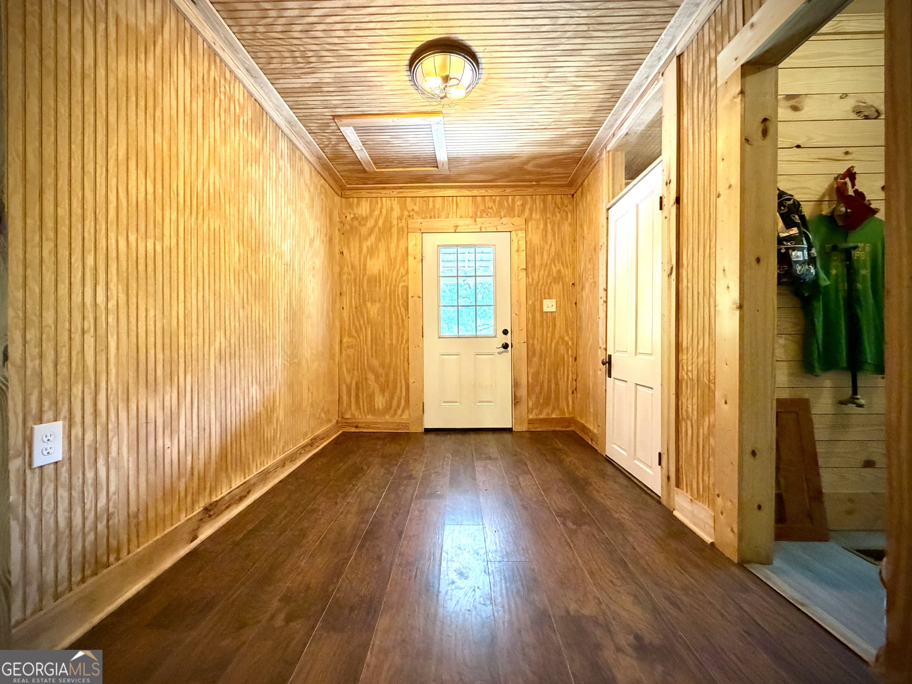 Wood-paneled entry hallway with dark floors and a white divided-light door.