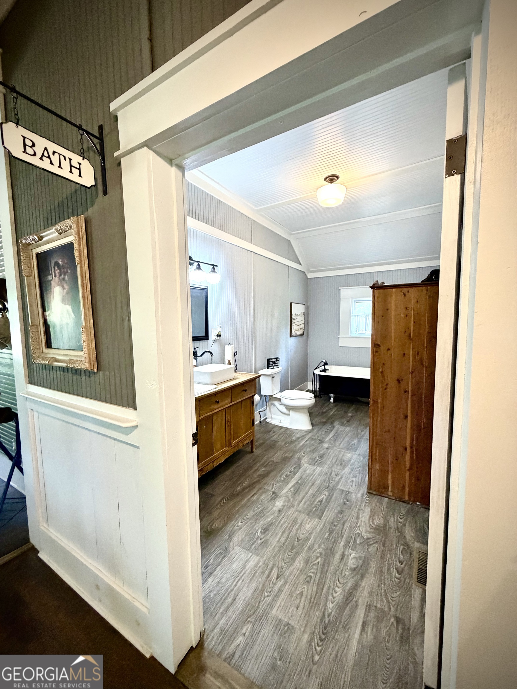 Bathroom with a freestanding tub, wood vanity, and gray wood-look flooring.