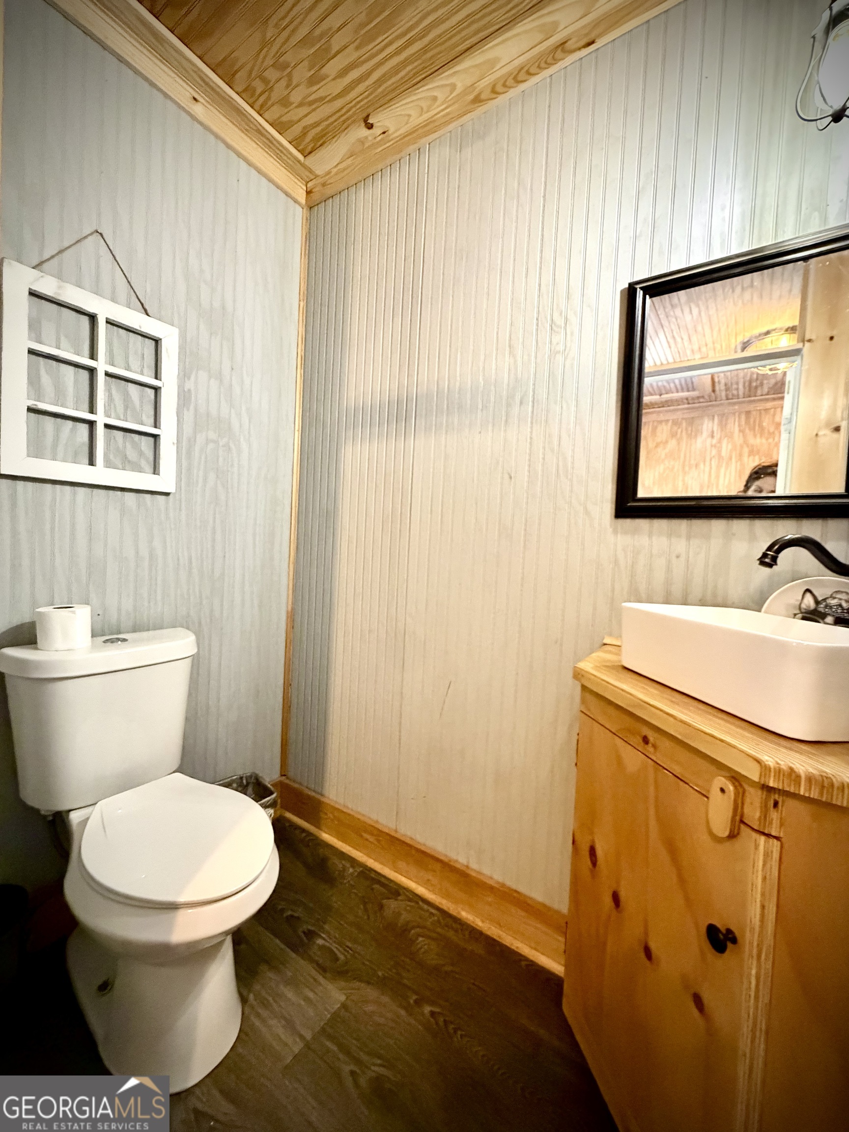 Bathroom with a wood vanity, vessel sink, beadboard walls, and plank ceiling.